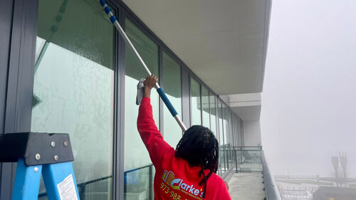 A team member of Clarke's Service Professionals gently cleaning the window.