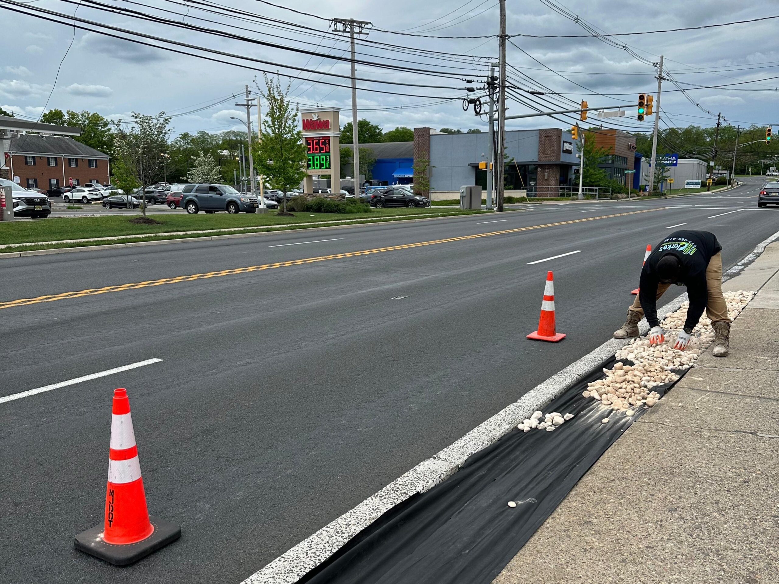 Clarke's Service Professionals is positioning cones along the road, simultaneously cleaning stones.