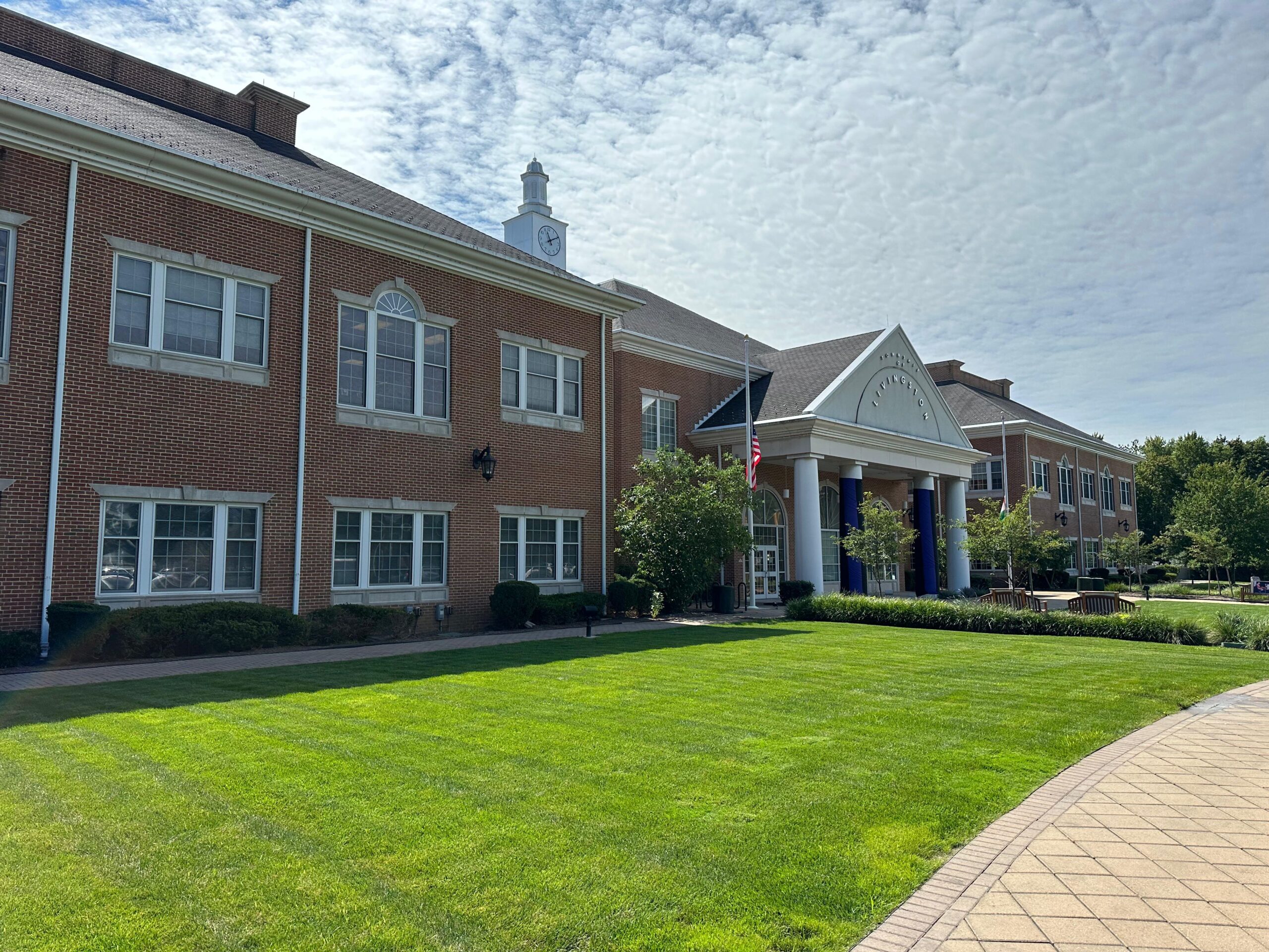 A large brick building with a lawn and trees and the windows are perfectly cleaned by Clarke's Service Professionals.