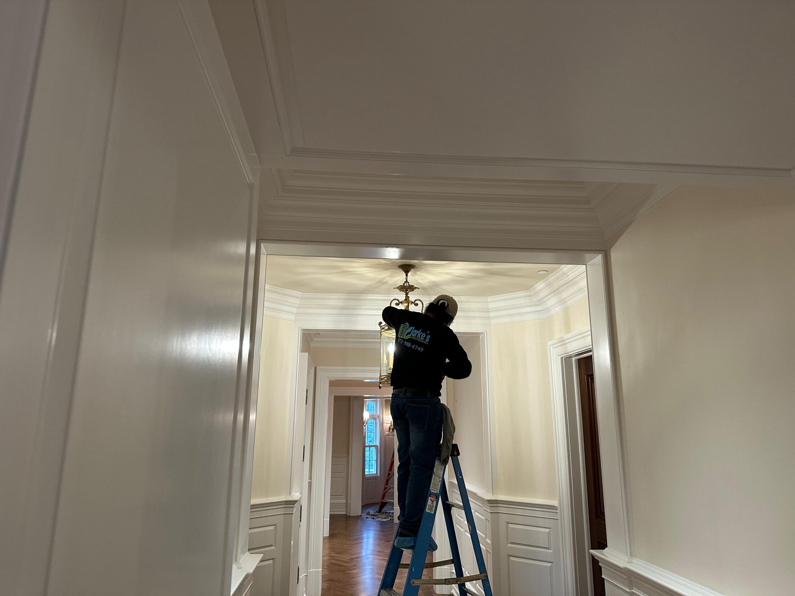Clarkes professional on a ladder providing chandelier cleaning services