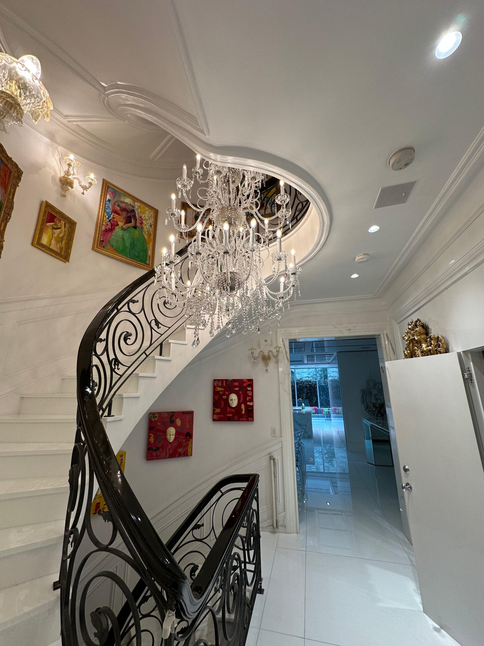 Elegant staircase with chandelier and wall art in a home, cleaned by Clarke's Service Professionals.