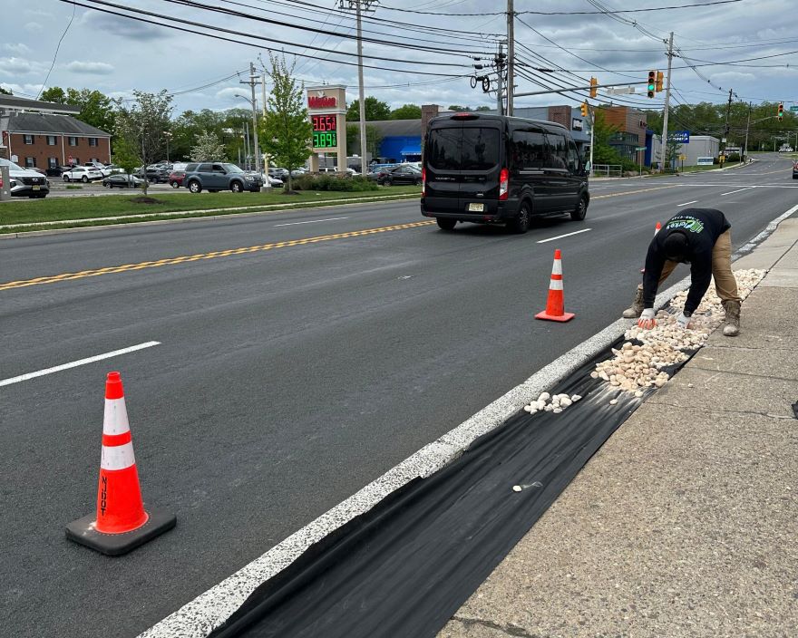 Clarke's Service Professionals Worker placing stones beside a road near traffic cones
