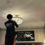 Clarke's Service Professionals Electrician installing crystal chandelier in Iconic restaurant