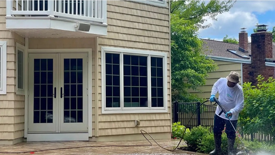 Clarke's Service Professionals worker doing Pressure washing a patio and house exterior.