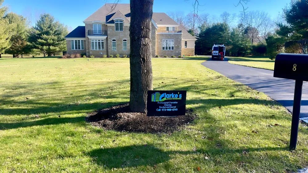 Large house with lush lawn featuring Clarke's lawn care sign
