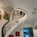 Elegant spiral staircase with a grand crystal chandelier and vibrant artwork
