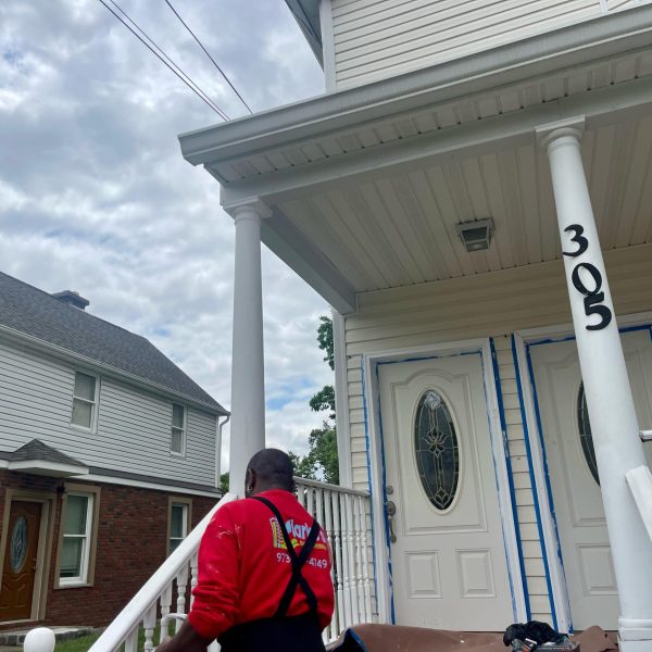 Clarke's Service Professionals Painter prepping porch columns and doors for painting at 305