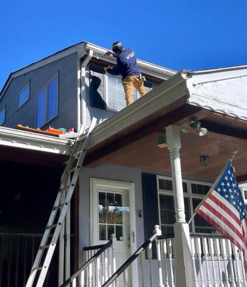 3 Clarke's Service Professionals Painter on ladder applying siding to house exterior