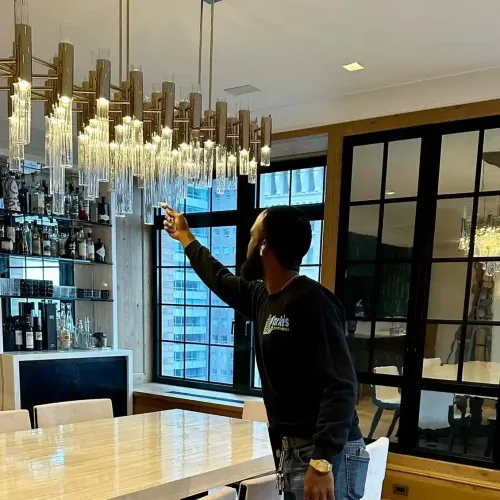 A clarkes handyman standing in front of a chandelier checking the cleanliness.