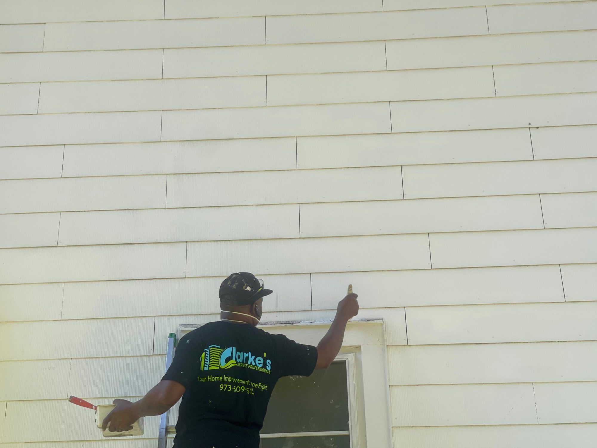 Clarke's professional painting the exterior wall of a building